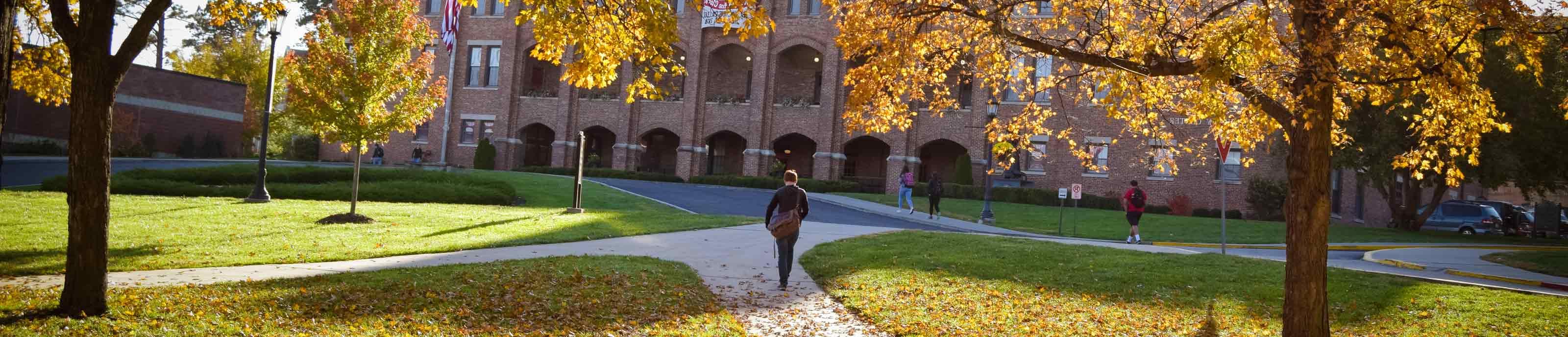 A student walks on an autumn Benedictine College campus